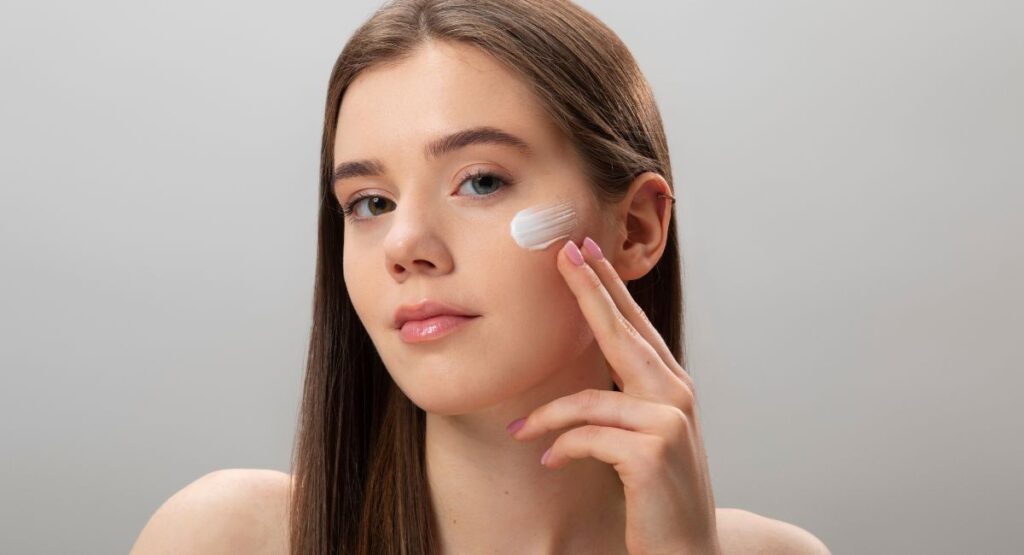 Young woman with smooth skin applying Sunbetter sunscreen cream to her cheek with fingertips