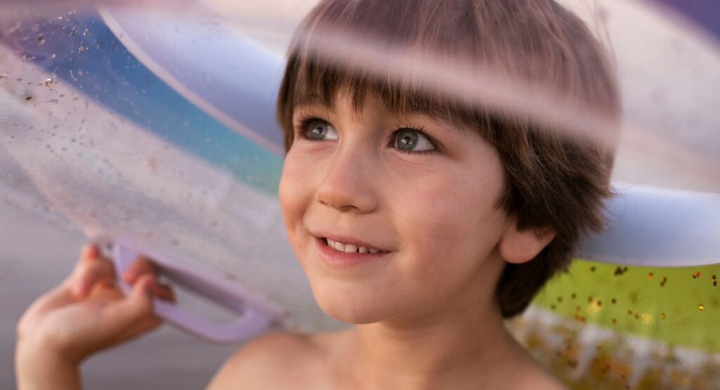 Child protected by Heliocare 360 Pediatrics Mineral Sunscreen SPF50 50ml staying safe under beach umbrella