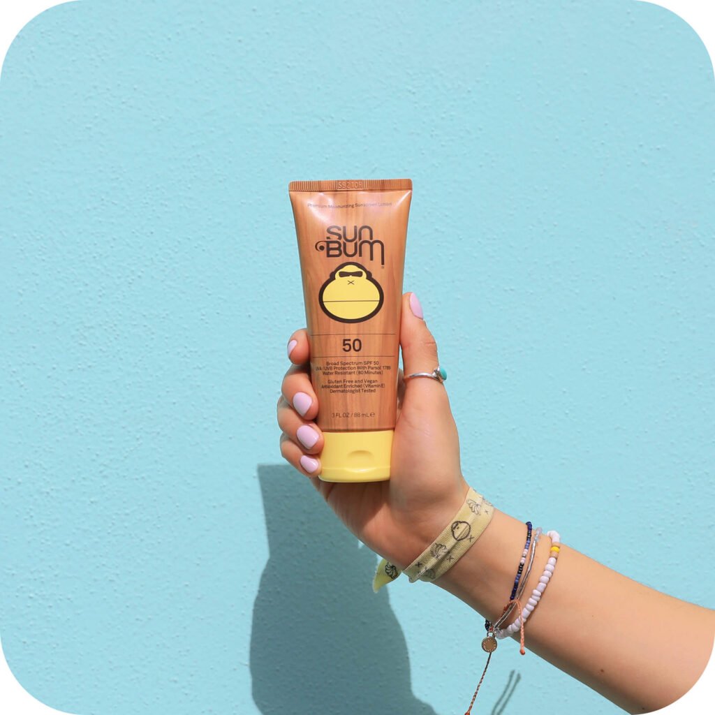 Sun Bum Original SPF 50 sunscreen in signature gold packaging against blue background, showing the brand's most popular formula