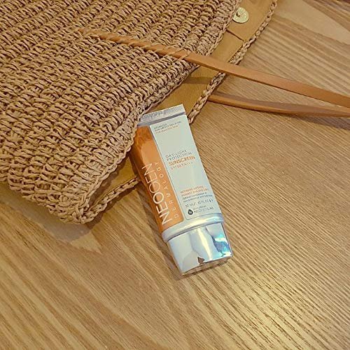 Neogen Dermalogy sunscreen SPF50 placed beside woven straw beach bag on wooden surface, perfect for summer protection.
